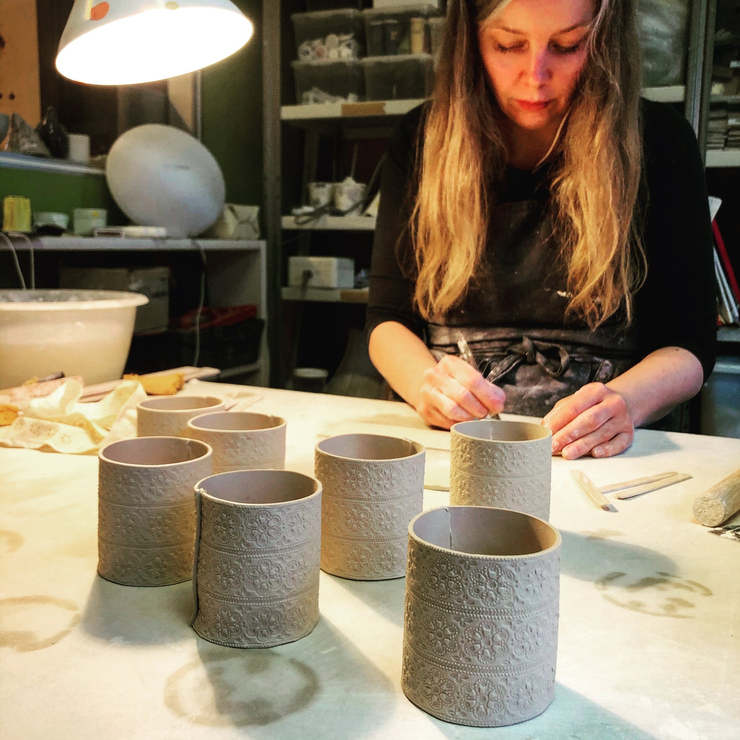 Louise Mathiesen står i værkstedet og arbejder på lysestager.