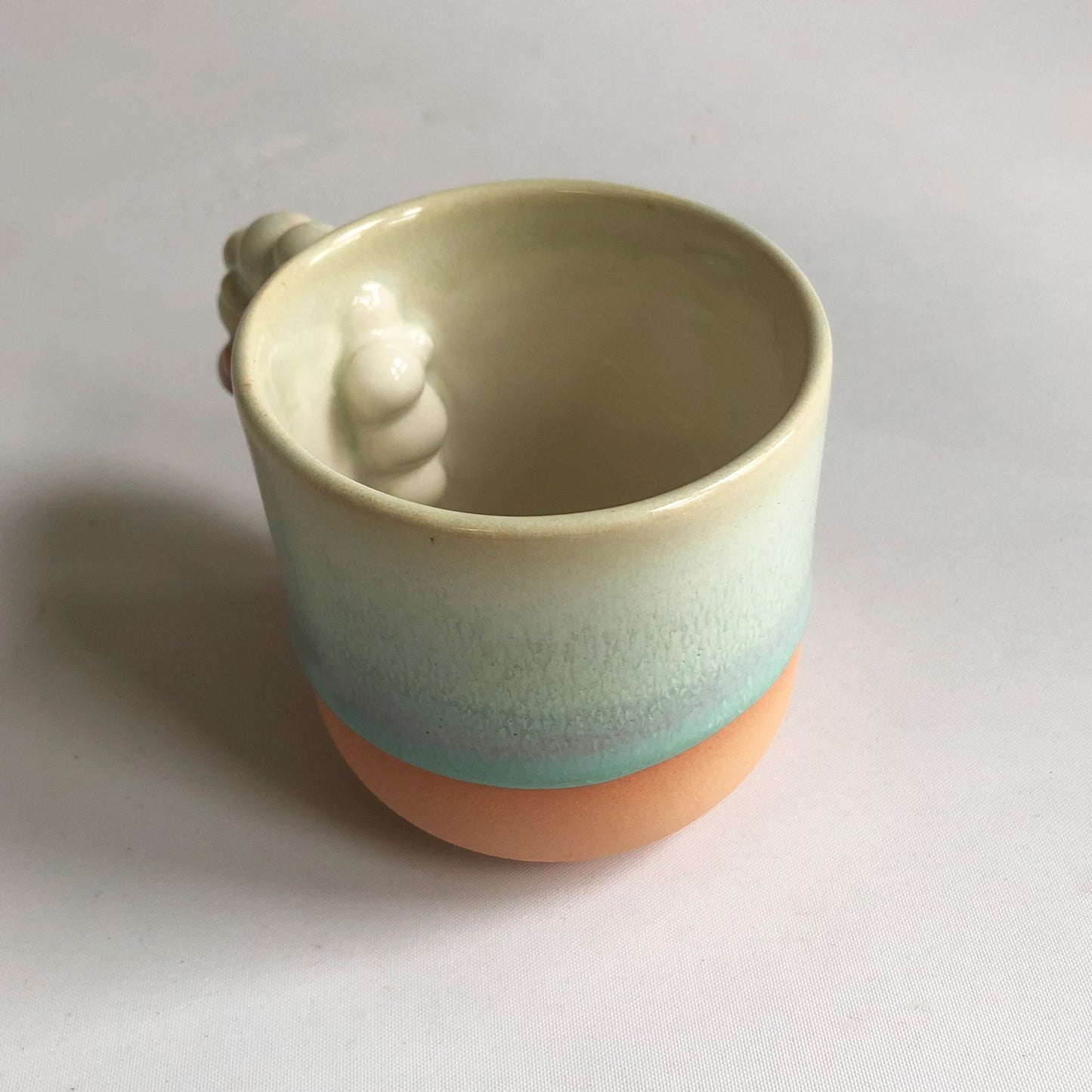 Little cup with matte peach colored bottum and green glaze