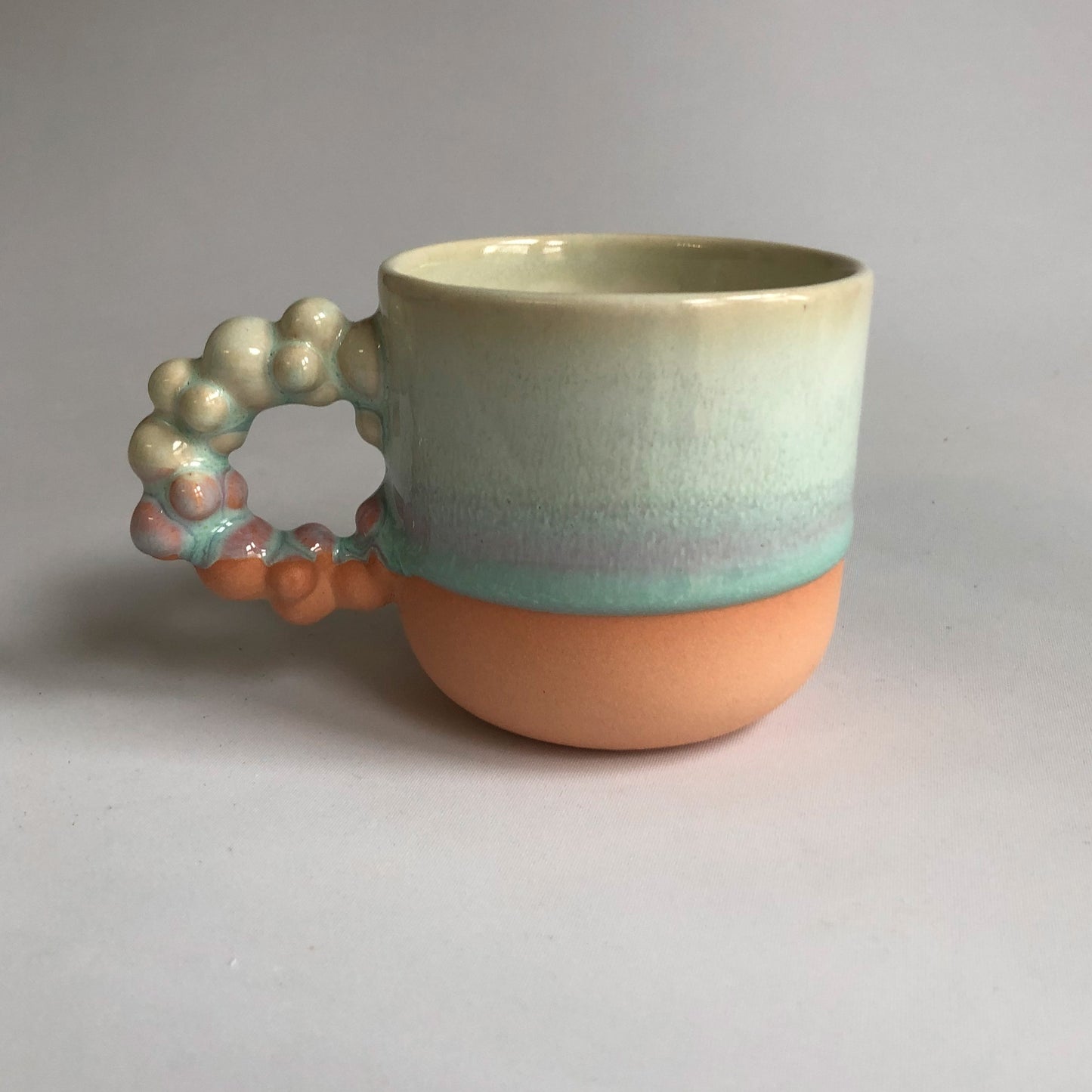 Little cup with matte peach colored bottum and green glaze