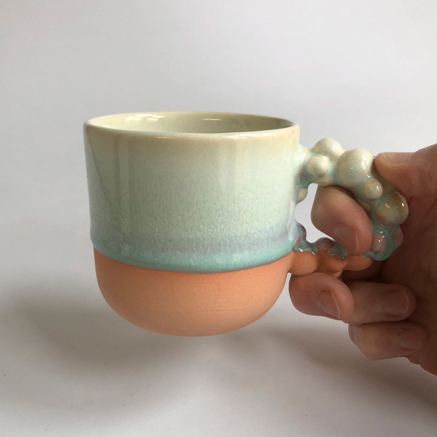 Little cup with matte peach colored bottum and green glaze