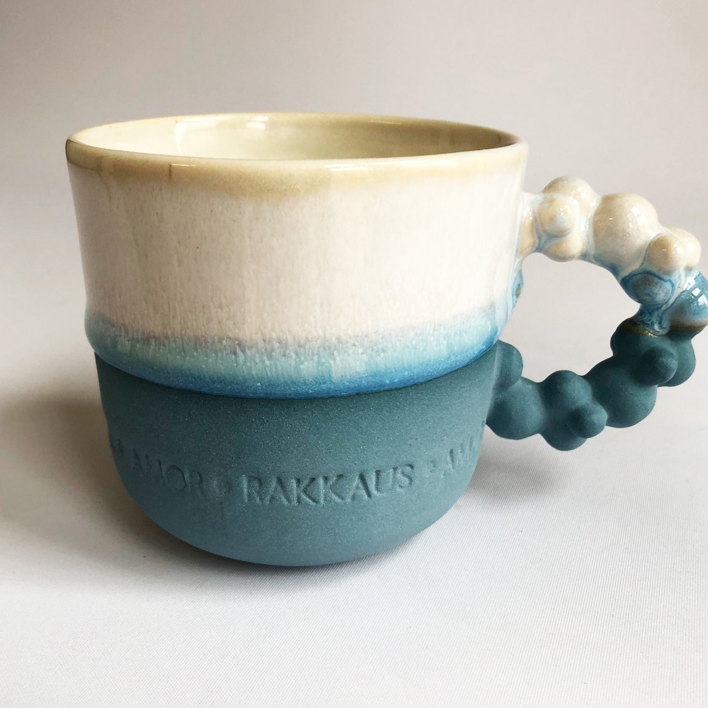 Big cup with text. The cup has a blue matte bottom and white glaze