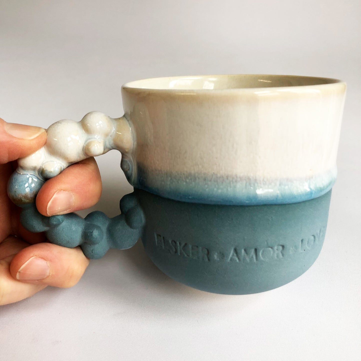 Big cup with text. The cup has a blue matte bottom and white glaze