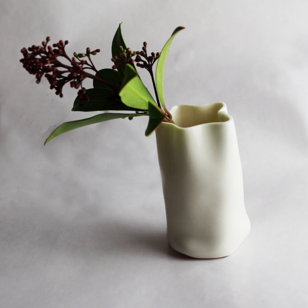 Lille hvid stjerneformet vase med en blomst i. Set forfra.