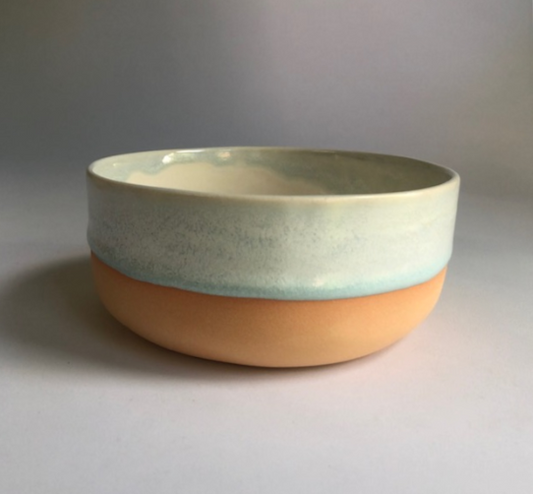Small bowl with matte coral-colored base and ice-blue glaze