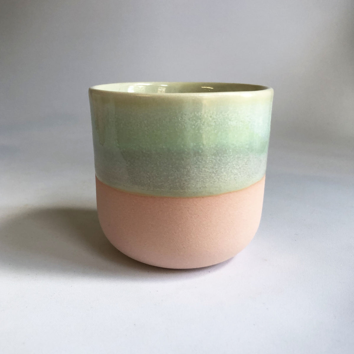 Little cup without handle with a matte light pink base and green glaze