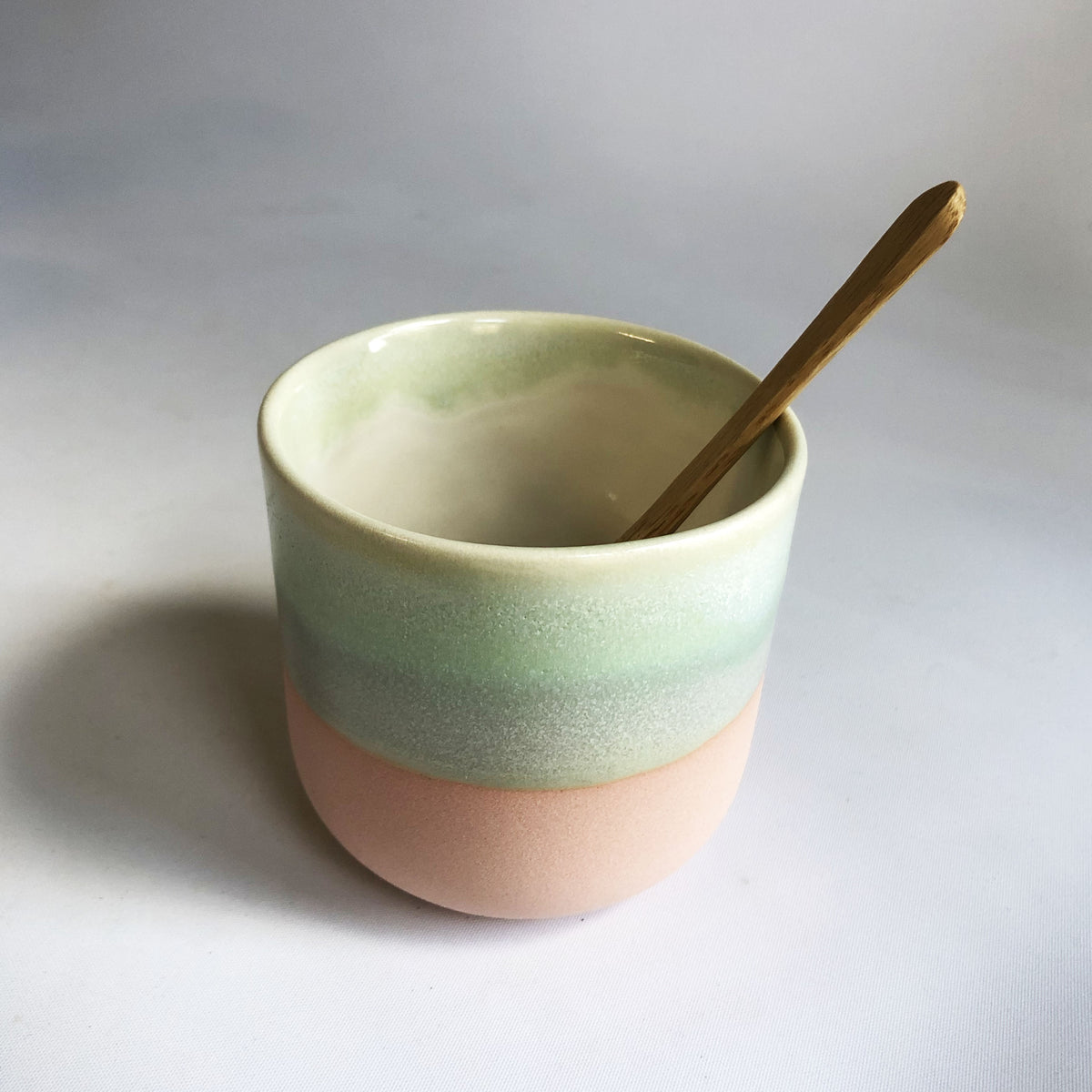Little cup without handle with a matte light pink base and green glaze