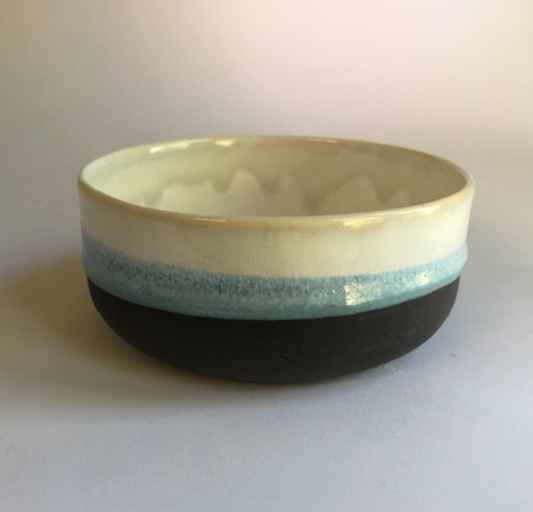 Small bowl with a matte black base and ice-blue glaze