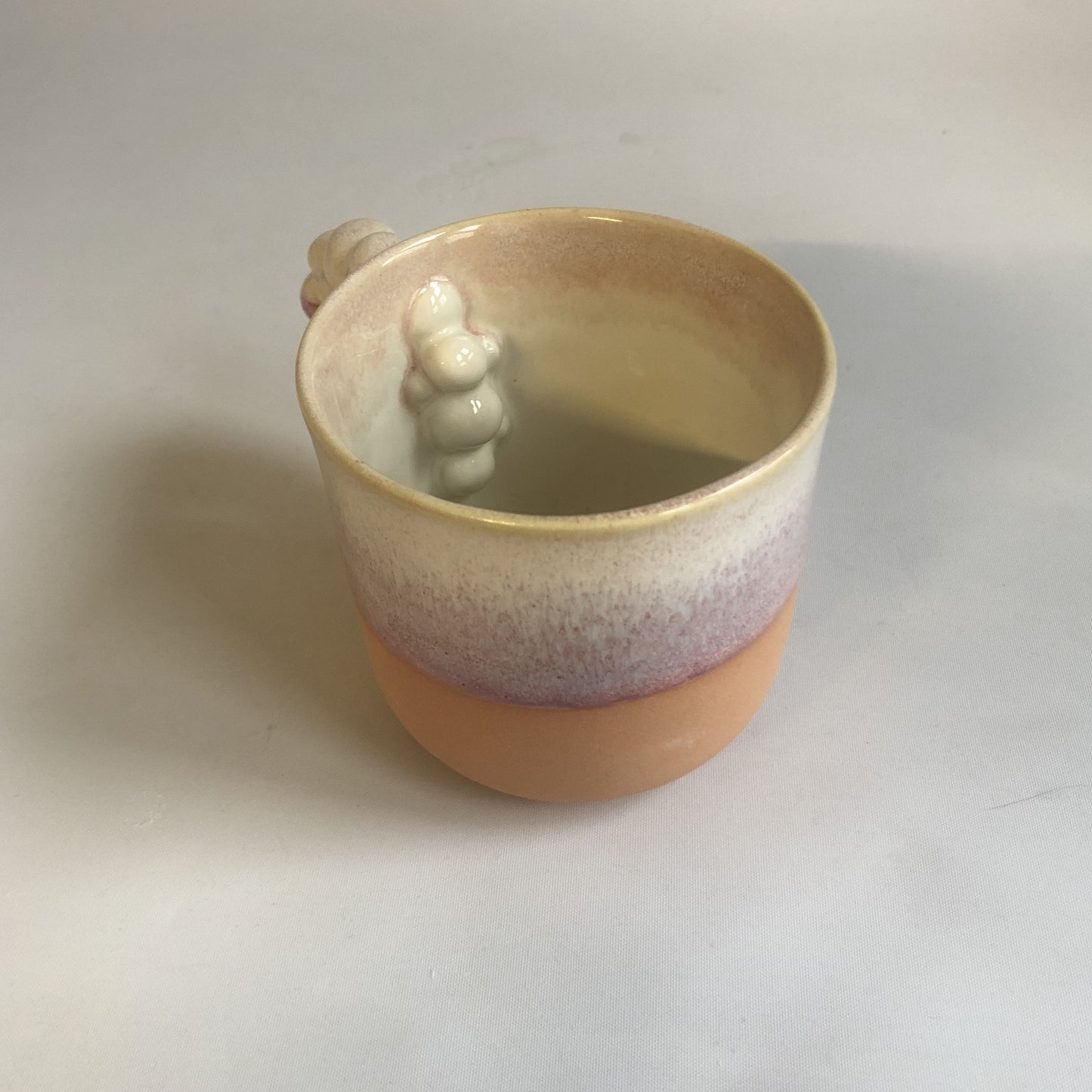 Stor kop med mat ferskenfarvet bund og lyserød glasur