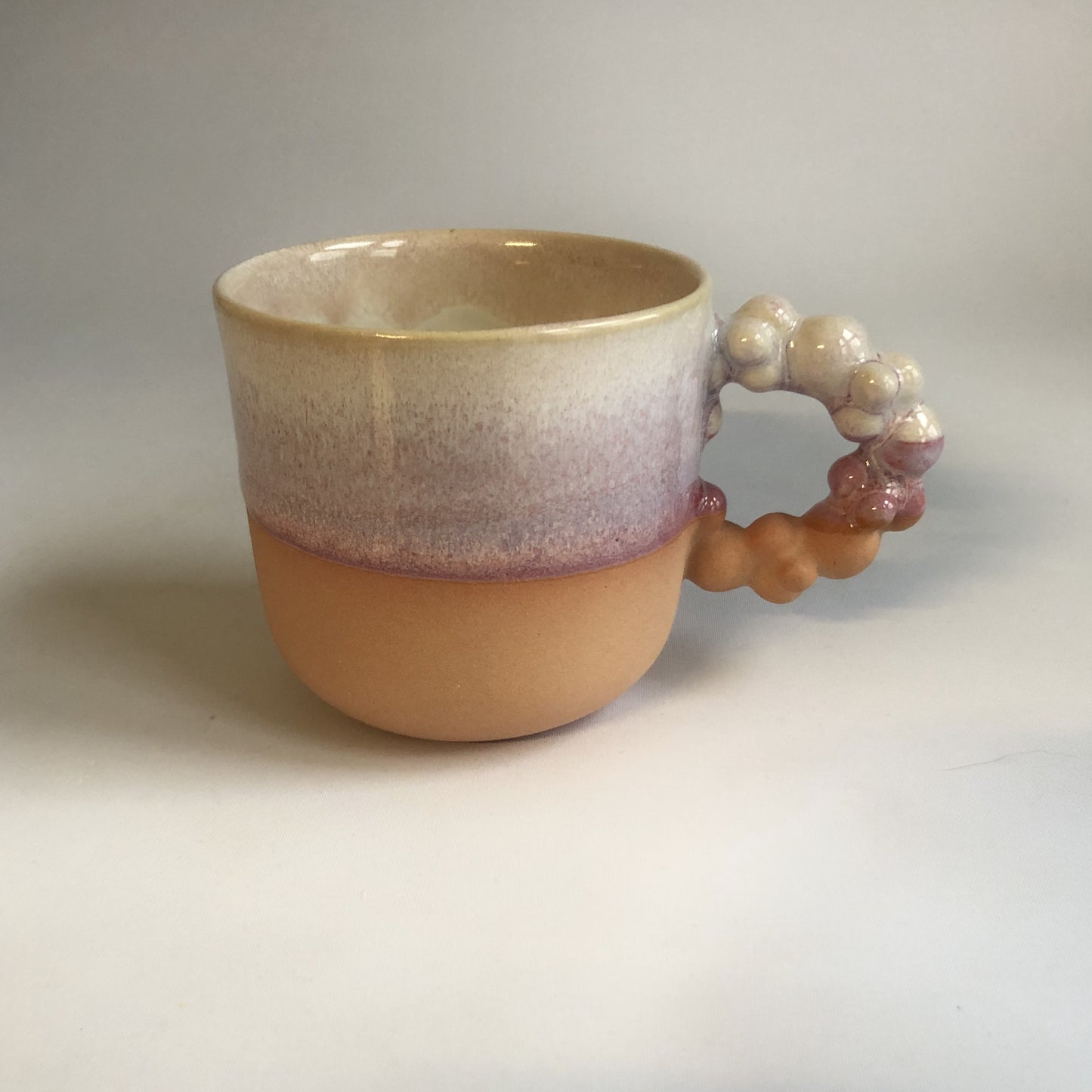 Stor kop med mat ferskenfarvet bund og lyserød glasur