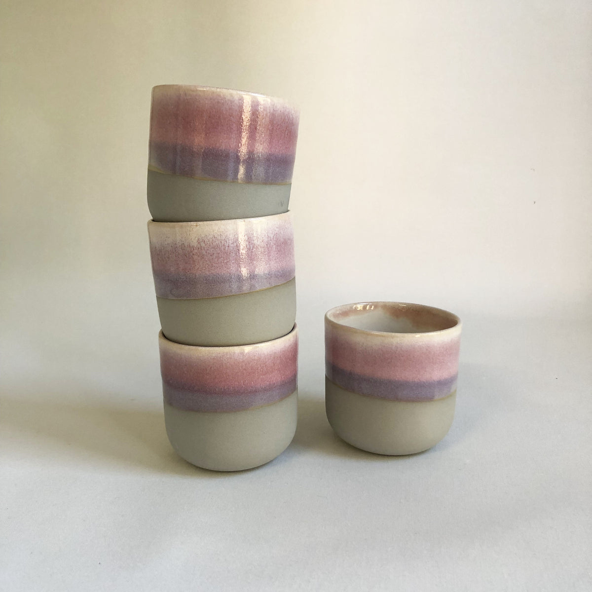 Large handleless cup with a matte grey bottom and light pink glaze