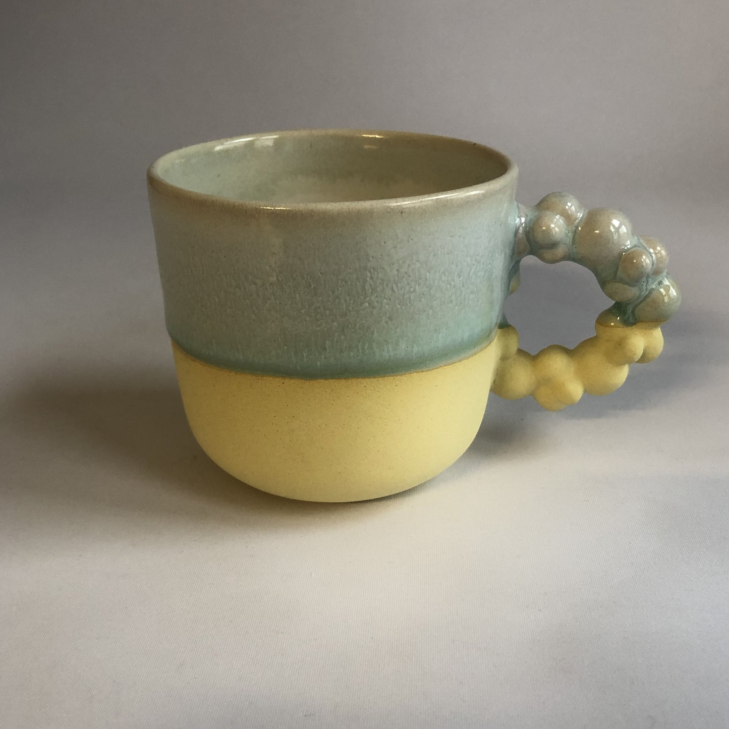 Stor kop med mat gul bund og grøn glasur